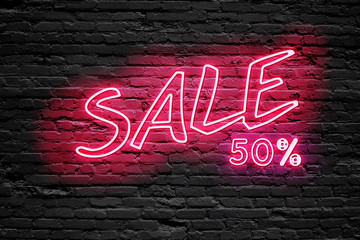 SALE 50 % Percent. fluorescent Neon tube Sign on dark brick wall. Front view. Can be used for online banner ads or background. night moment.