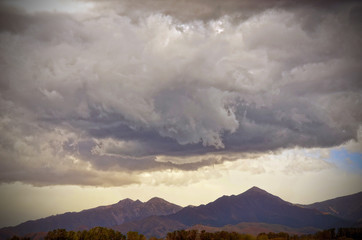 Dramatic storm clouds developing over mountains and farmland, south island, New Zealand. Toned image.