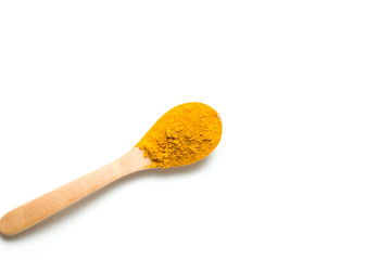 Turmeric powder in a wooden spoon isolated over white background
