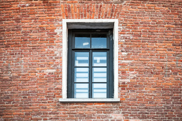 Window with black frame in old brick wall