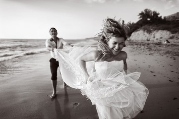 Romantic couple having fun on the beach. Young  in love, Attractive man and woman enjoying  evening  the , Holding hands watching the sunset
