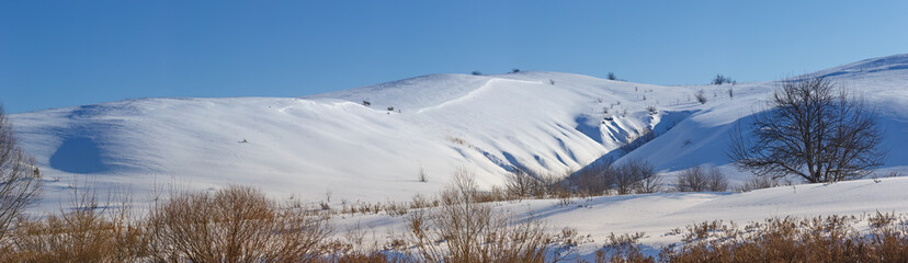 Fototapeta premium Panoramic view of snow-covered hills in central Russia. Winter s