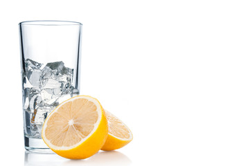 Glass with ice cubes and lemon slices on white background