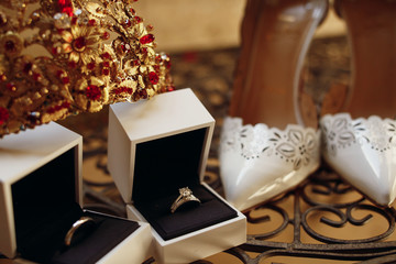 Look from above at golden crown, wedding rings and white shoes s