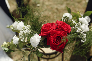 White and red roses pinned to steel chair