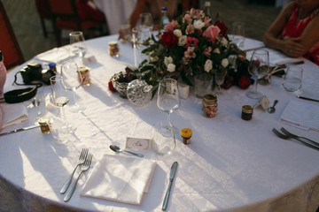 Shadows of trees lie over white dinner table decorated with bouq
