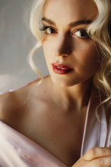 Stunning blonde with seductive red lips poses in pink silk robe