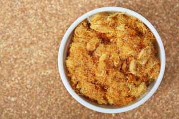 dried pork floss in white cup on cork board