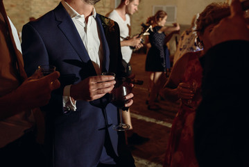 Men hold glasses with wine and smoke cigars standing outside
