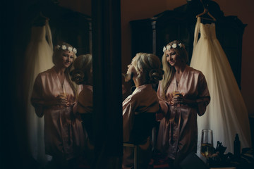 Bridesmaid in flower wreath stands behind gorgeous blonde bride