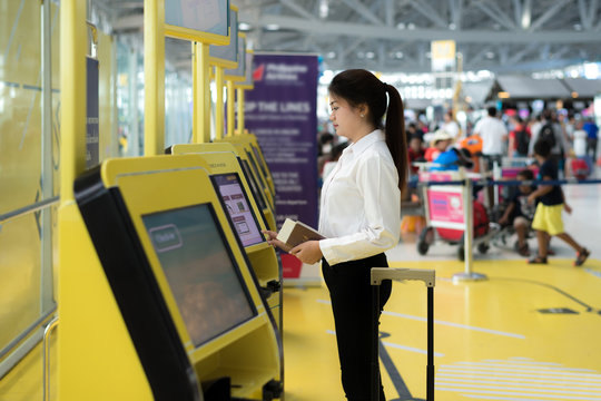 Young Asian businesswoman using self check-in kiosks in airport.