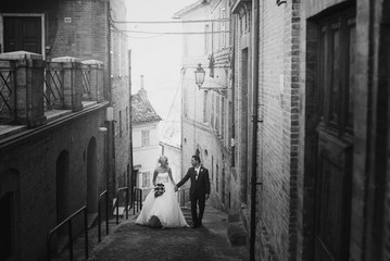 Bride and groom look at each other walking along the narrow Ital