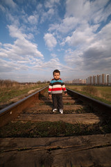 Fototapeta na wymiar little beautiful boy plays on railroad