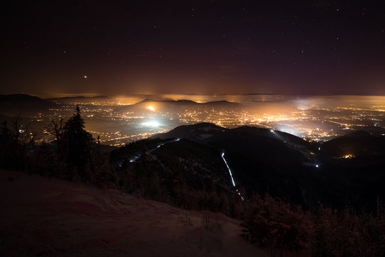 night mountain photo with glowing city lights and starry sky