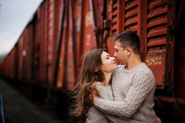 Young couple wearing on tied warm sweaters hugging in love at ra