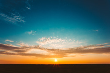 Sunset Sunrise Over Field Or Meadow. Bright Dramatic Sky And Dar