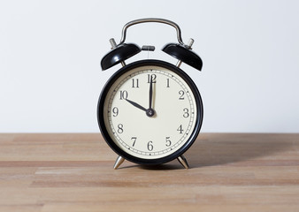 It is ten o'clock. The time is 10:00 am or pm. Retro clock isolated on a wooden surface. White background. Copy space and cut.