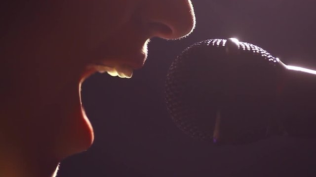 Close up footage of a woman screaming to a microphone.