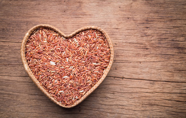 Organic rice grain in heart shape bamboo basket on wooden backgr