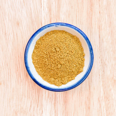 curry powder in bowl on wood floor background.