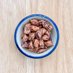 Raw Organic Pinto beans in bowl on wood floor background.
