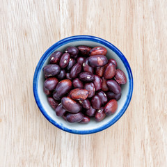 Kidney bean in bowl on wood floor background.