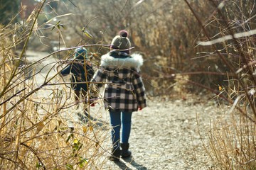 shallow DOF of brother and sister walking in woods during winter