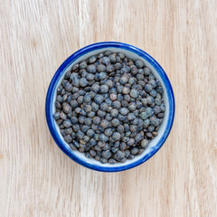 Fototapeta na wymiar Green lentils in bowl on wood floor background.