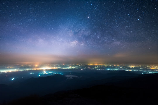 Night landscape of Milky way above the light of countryside area and mountain.