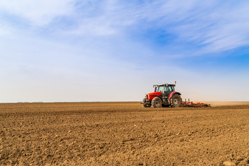 Obraz premium Farmer in tractor preparing land with seedbed cultivator