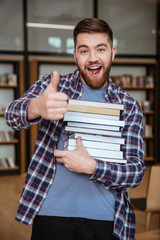 Obraz premium Portrait of a smiling man student holding books in library