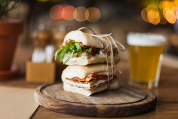 Closeup tasty and appetizing sandwich with arugula and meat on the wooden plate in the restaurant