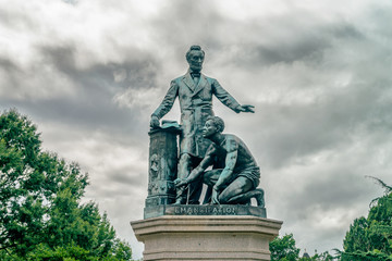 The bronze statue features President Lincoln standing with his left arm out-stretched over a...