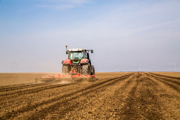 Obraz premium Farmer in tractor preparing land with seedbed cultivator