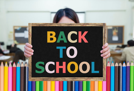 BACK TO SCHOOL message on the blackboard wooden frame on hand woman with Color pencils footer. Education concept.