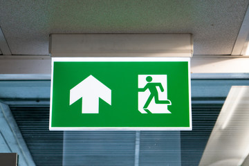 green emergency exit sign showing the way to escape.