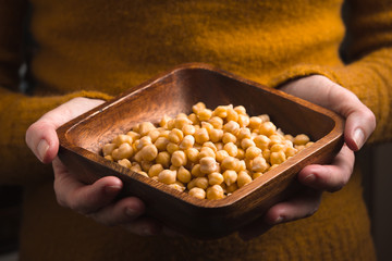 Wooden bowl with chickpeas in the hands horizontal