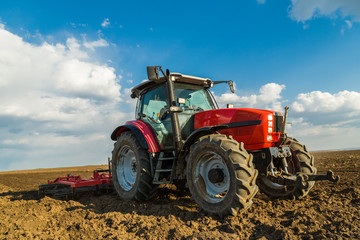 Fototapeta premium Farmer in tractor preparing land with seedbed cultivator