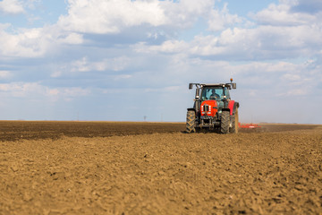 Fototapeta premium Farmer in tractor preparing land with seedbed cultivator
