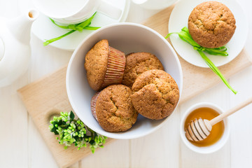 Tea time: homemade banana muffins, honey, bananas and tea settings on white wooden table. Selective focus