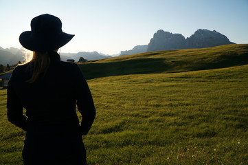 Wanderin genießt Morgensonne und Aussicht auf Wiese und Berge in Südtirol / Seiser Alm / Gröden
