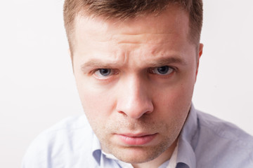 Young man frowned angrily looks into the camera at close range