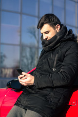 young man sending message near modern  sport car