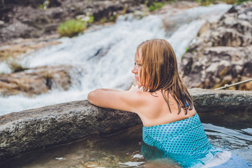 Geothermal spa. Woman relaxing in hot spring pool against the background of a waterfall