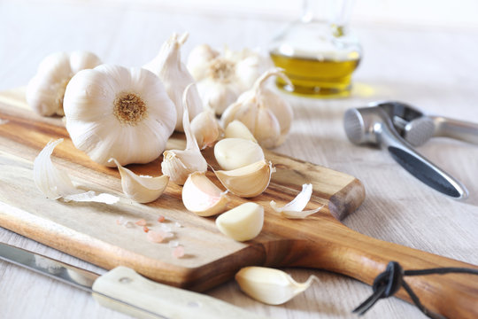 Bulbs of garlic, garlic press and olive oil