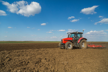 Farmer in tractor preparing land with seedbed cultivator as part of pre seeding activities in early spring season of agricultural works at farmlands.