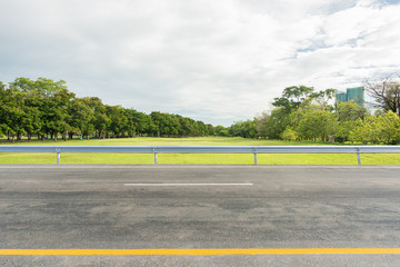Side view of asphalt road with park in city