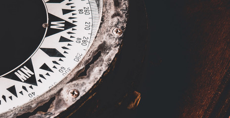 Close-up of ancient boat compass aboard on old vintage wood. Vintage ship compass.