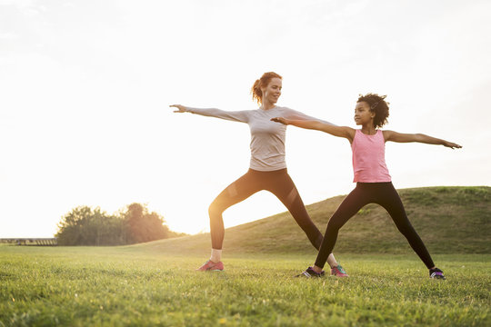 Mother and daughter doing yoga in meadow