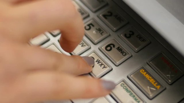 Entering pin code in bank cash machine for money withdrawal
